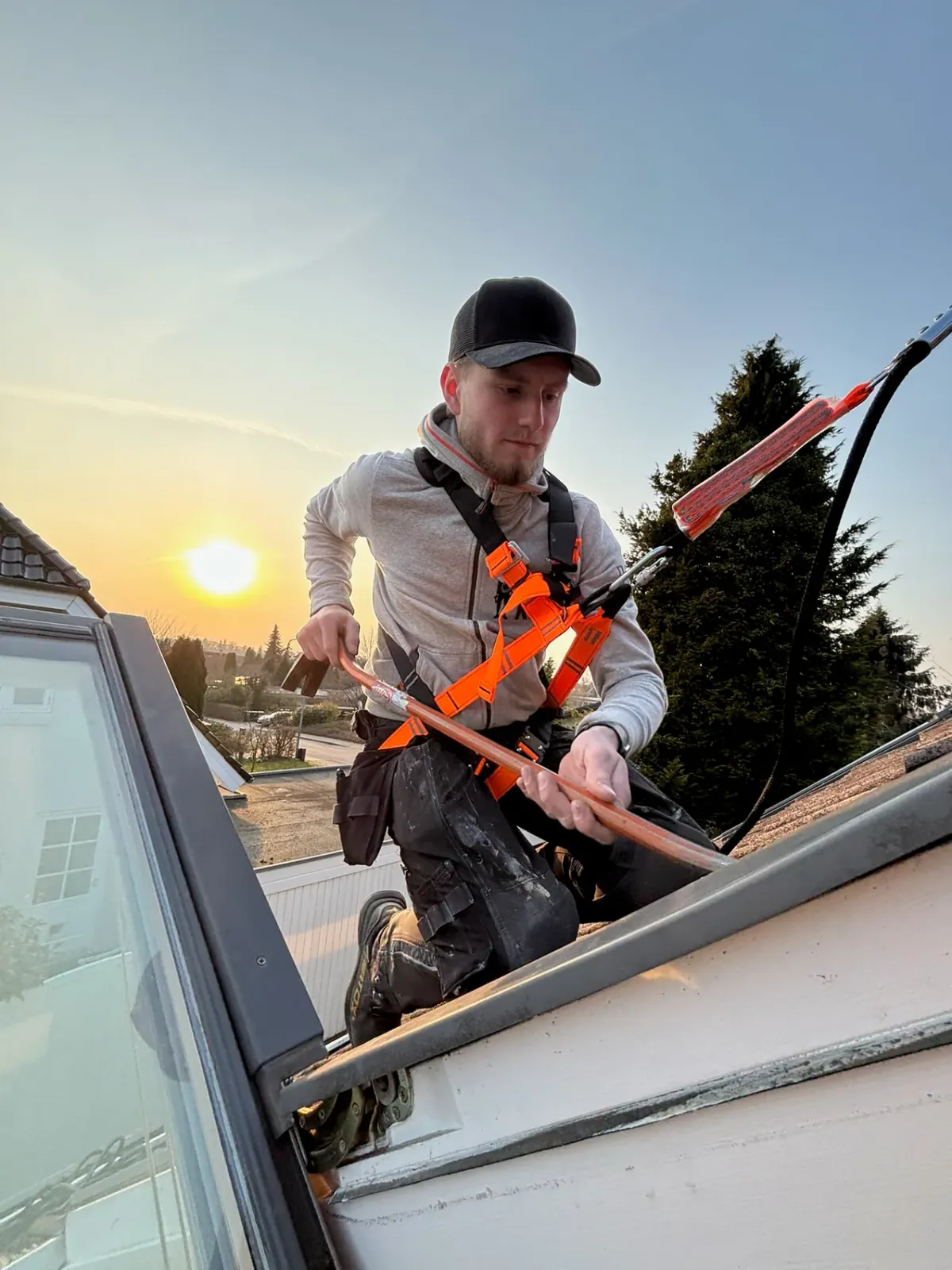Ung tømrer fra GK Tømrerentreprise arbejder på tag i solnedgang i Storkøbenhavn