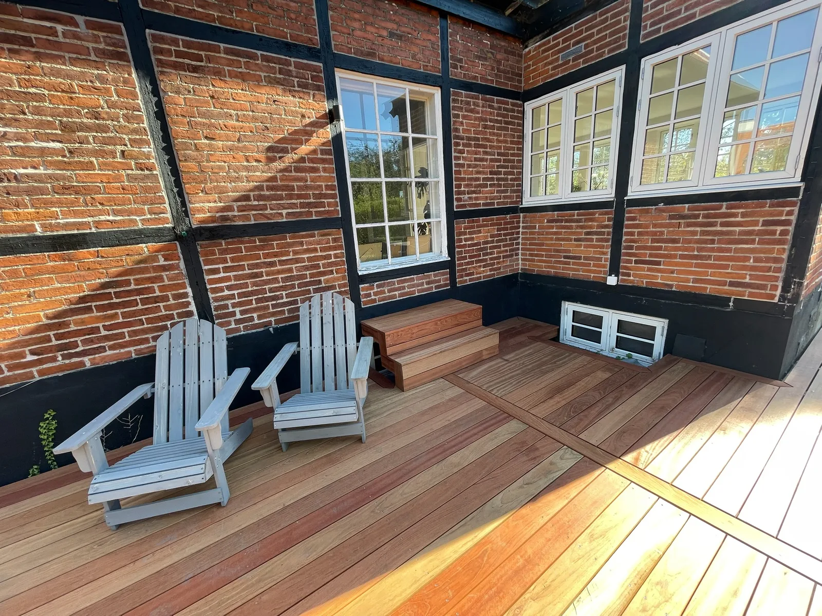 Detalje af hårdttræ-terrasse i hjørne med loungestole